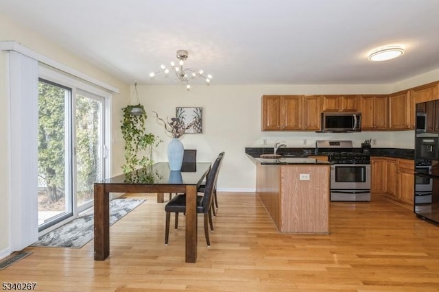 kitchen with light wood-style flooring, stainless steel appliances, a peninsula, visible vents, and dark countertops