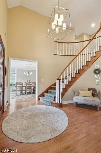 interior space featuring stairway, a notable chandelier, wood finished floors, and high vaulted ceiling