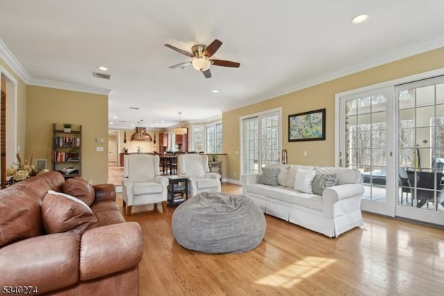 living room featuring visible vents, a healthy amount of sunlight, wood finished floors, and crown molding