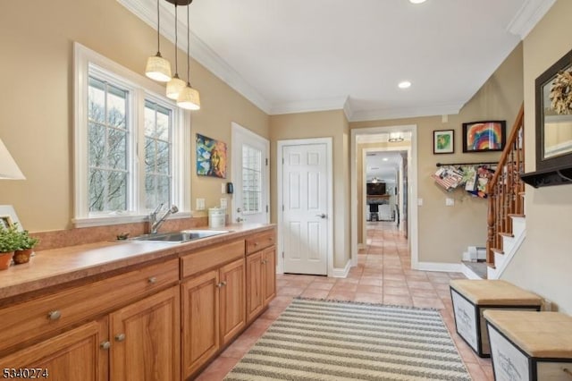 kitchen featuring light countertops, pendant lighting, ornamental molding, and a sink