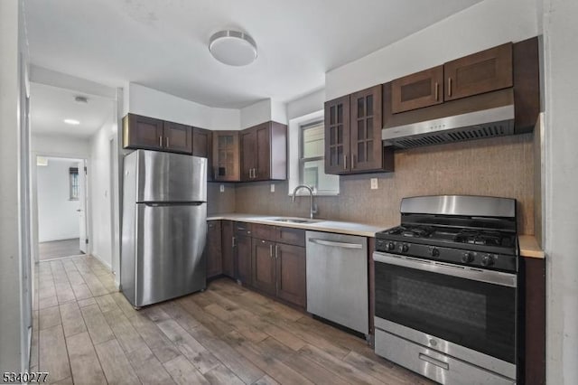 kitchen with wood finished floors, stainless steel appliances, a sink, and light countertops