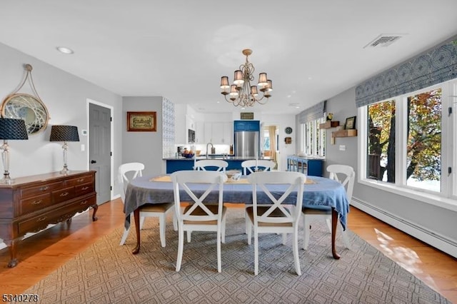 dining room featuring a chandelier, a baseboard radiator, recessed lighting, visible vents, and light wood finished floors