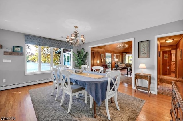 dining space featuring a chandelier, a baseboard radiator, light wood-style flooring, and baseboards