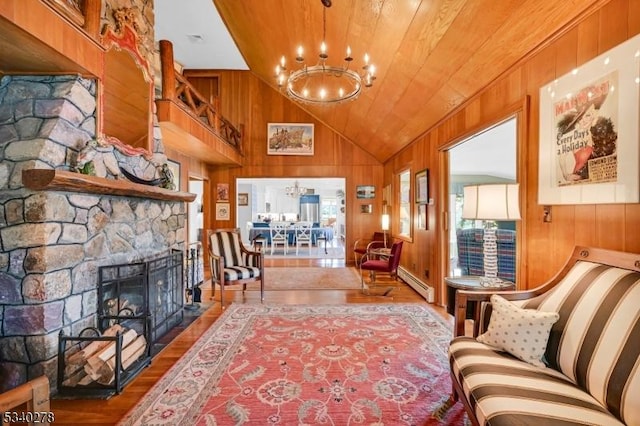 living area with wood finished floors, baseboard heating, wood walls, a fireplace, and a chandelier