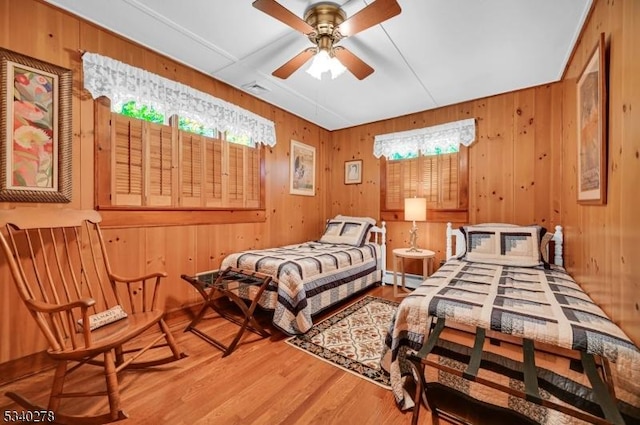 bedroom with a baseboard radiator, wooden walls, and wood finished floors