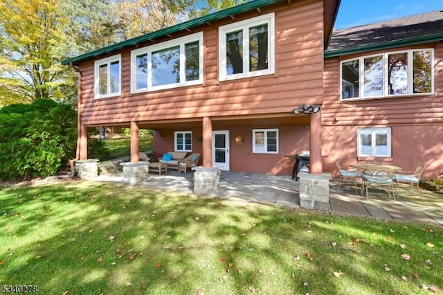 back of property with outdoor lounge area, a patio, and a lawn