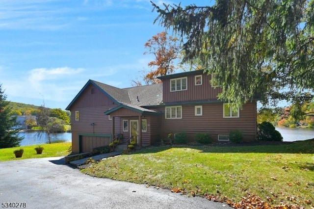 view of front of home with a front lawn and a water view