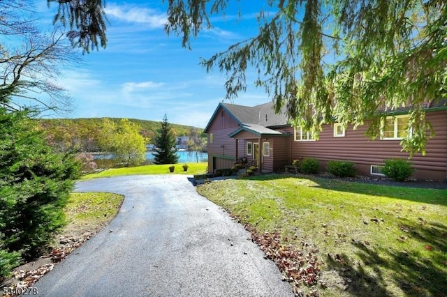 view of front of home with driveway, log veneer siding, and a front yard