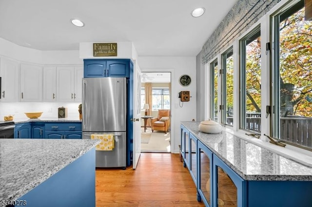 kitchen with light wood-style floors, freestanding refrigerator, white cabinets, light stone countertops, and blue cabinets