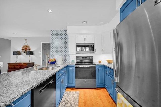 kitchen featuring light wood-type flooring, blue cabinetry, appliances with stainless steel finishes, and a sink