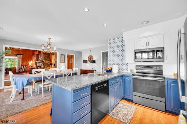 kitchen featuring a peninsula, a sink, white cabinetry, blue cabinetry, and appliances with stainless steel finishes