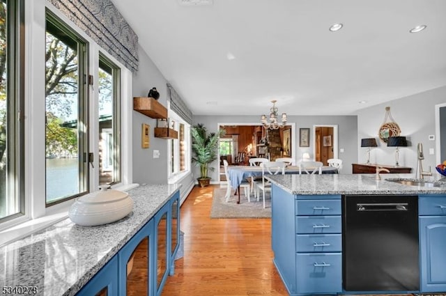 kitchen with black dishwasher, blue cabinetry, a wealth of natural light, a sink, and light wood-type flooring