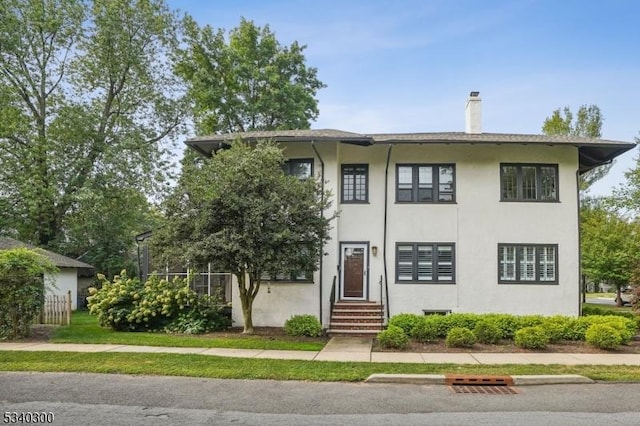 view of front of home with entry steps, a chimney, and stucco siding