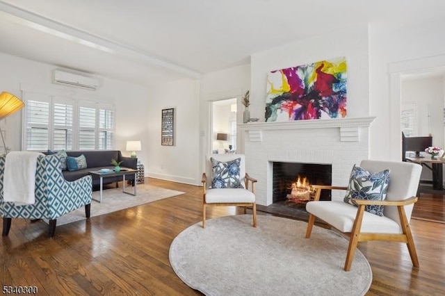 living room with a brick fireplace, an AC wall unit, baseboards, and wood finished floors