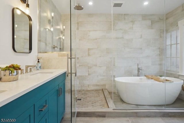 full bath featuring a stall shower, a freestanding tub, visible vents, and tile walls