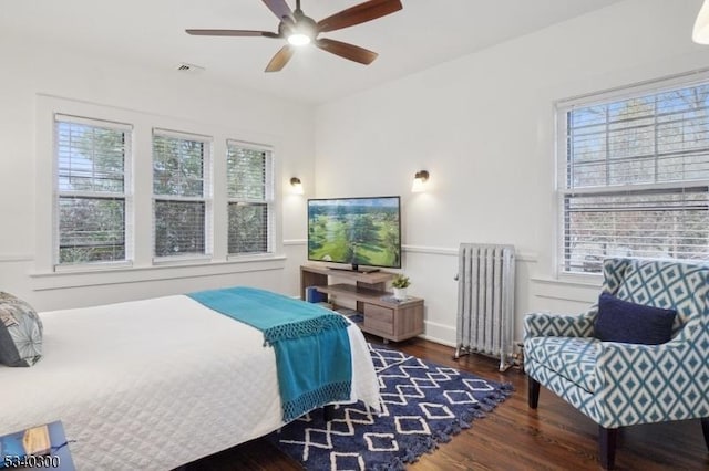 bedroom featuring ceiling fan, wood finished floors, visible vents, and radiator