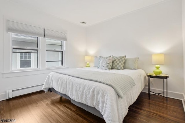 bedroom featuring baseboard heating, wood finished floors, and baseboards