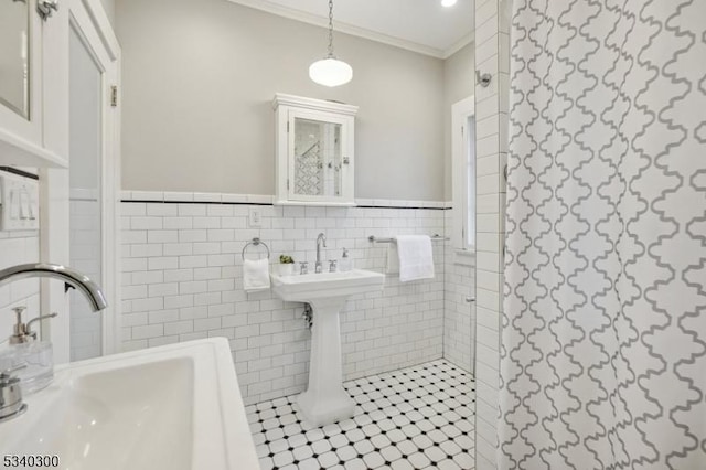 bathroom with ornamental molding, wainscoting, a sink, and tile walls