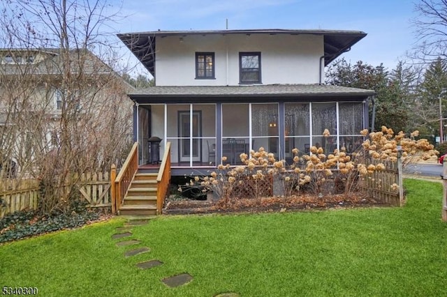 back of house featuring a sunroom, a lawn, fence, and stucco siding