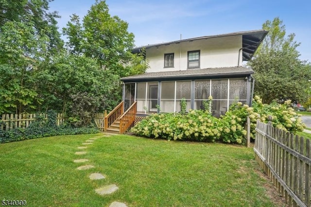 back of house featuring a yard, fence, a sunroom, and stucco siding