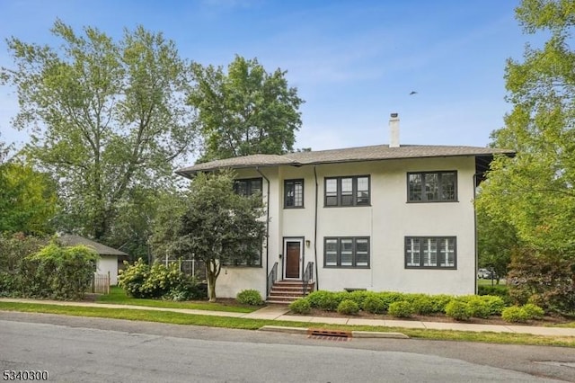 view of front of home with entry steps, a chimney, and stucco siding