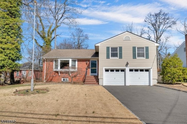 split level home featuring a garage, brick siding, and driveway