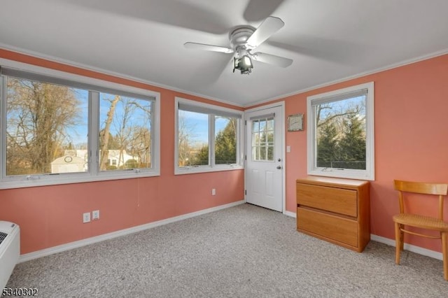 interior space featuring a ceiling fan, baseboards, light colored carpet, and crown molding