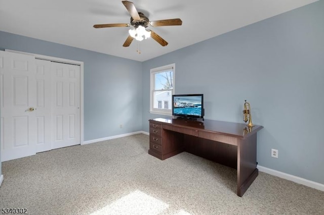 office space featuring a ceiling fan, baseboards, and light carpet