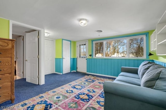 carpeted living room with visible vents, a healthy amount of sunlight, and wainscoting