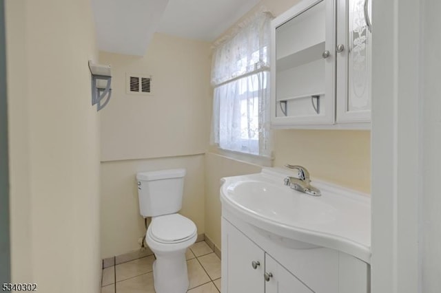 half bathroom featuring vanity, baseboards, visible vents, tile patterned floors, and toilet