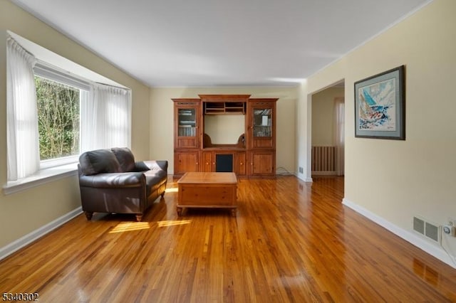 living room featuring visible vents, baseboards, and wood finished floors