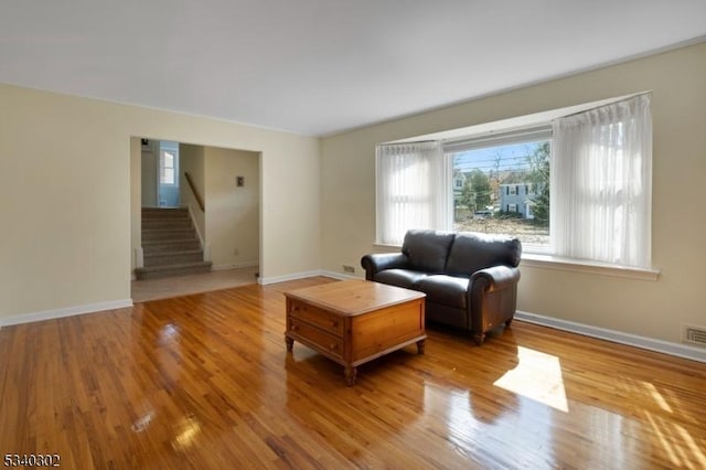 living area with stairway, baseboards, and wood finished floors