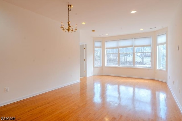 spare room with light wood-type flooring, a notable chandelier, baseboards, and recessed lighting