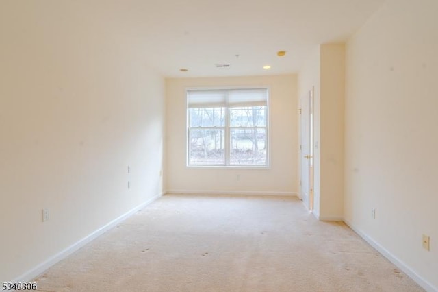 spare room featuring light carpet, visible vents, and baseboards