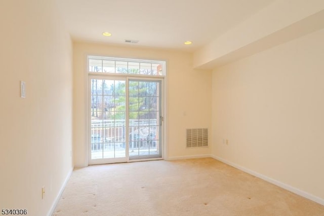 empty room with light colored carpet, visible vents, and baseboards