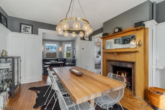 dining space with a decorative wall, a fireplace, and wood finished floors