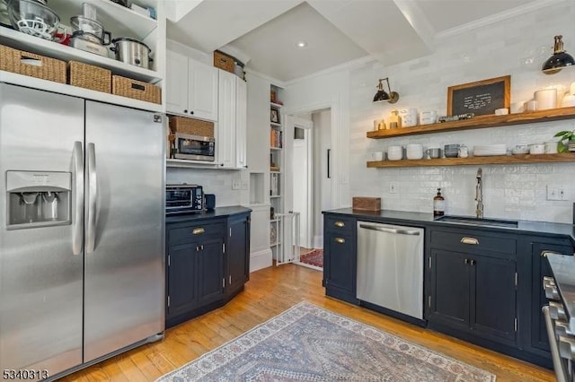 kitchen featuring open shelves, light wood-type flooring, ornamental molding, appliances with stainless steel finishes, and a sink