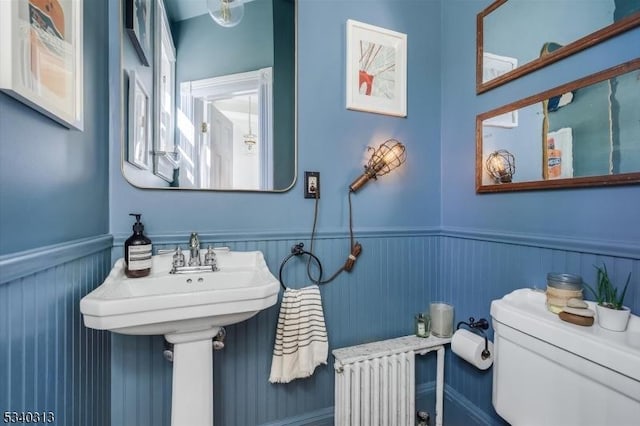 bathroom featuring toilet, a wainscoted wall, and a sink