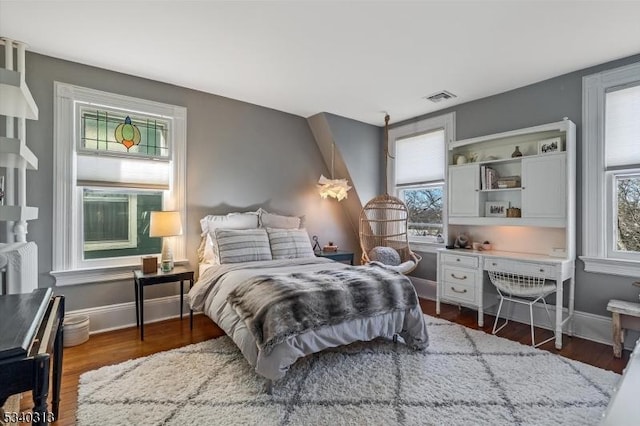 bedroom with wood finished floors, visible vents, and baseboards