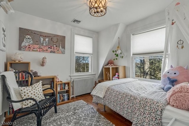 bedroom with visible vents, radiator heating unit, and wood finished floors