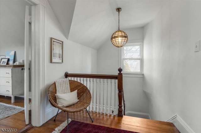 living area with an upstairs landing, baseboards, lofted ceiling, and wood finished floors