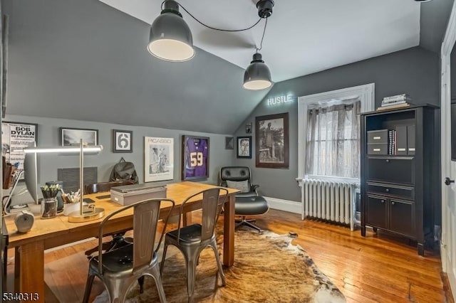 home office with vaulted ceiling, hardwood / wood-style flooring, radiator heating unit, and baseboards