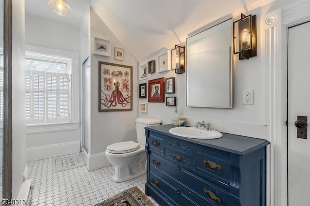 bathroom featuring vanity, baseboards, tile patterned flooring, vaulted ceiling, and toilet