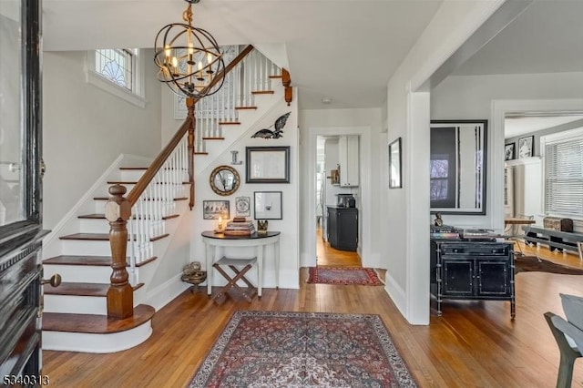 entrance foyer featuring stairway, baseboards, an inviting chandelier, and wood finished floors