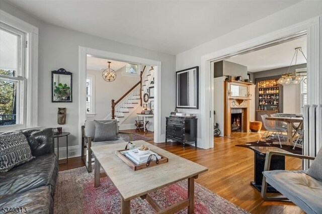 living room featuring stairs, plenty of natural light, wood finished floors, and a fireplace