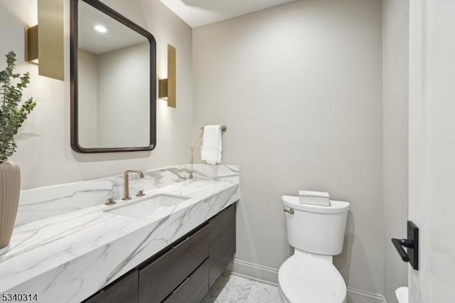 bathroom featuring toilet, vanity, and baseboards