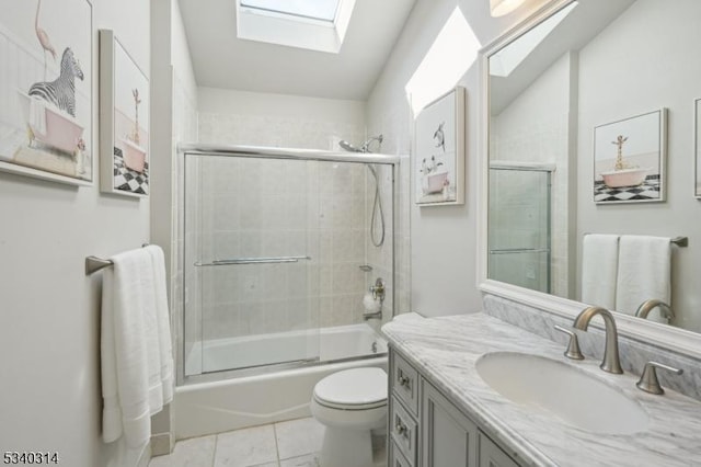 bathroom with a skylight, toilet, enclosed tub / shower combo, tile patterned floors, and vanity