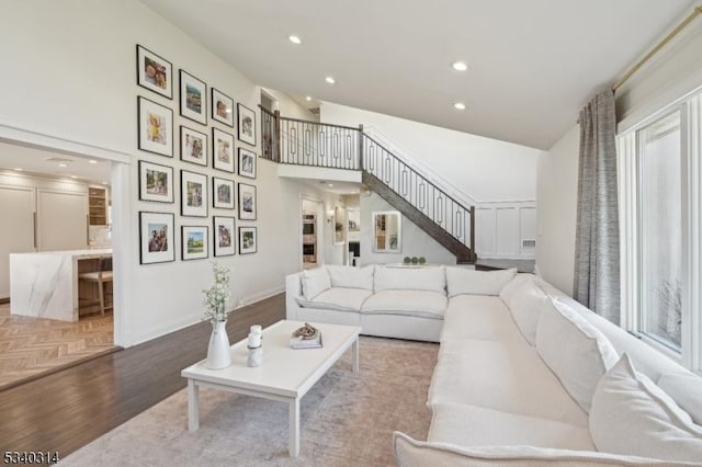 living room featuring baseboards, stairway, wood finished floors, a high ceiling, and recessed lighting