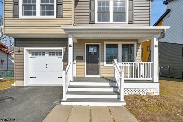 entrance to property featuring covered porch, driveway, and an attached garage