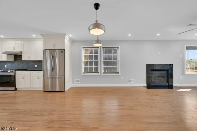 kitchen featuring appliances with stainless steel finishes, a fireplace with flush hearth, open floor plan, white cabinetry, and under cabinet range hood